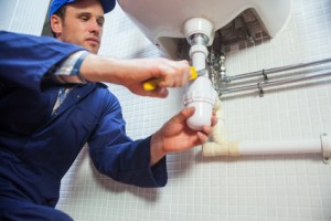 Frowning plumber repairing sink in public bathroom